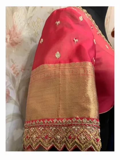A close-up of the sleeve of the red blouse, showing the detailed cutwork and embroidery along the edge.