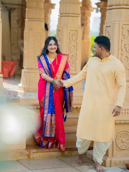 A playful and romantic shot of Shubham leading Jagruti by the hand. The soft foreground blur adds an artistic, dreamy quality to the image.