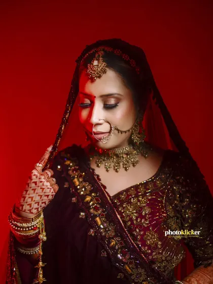 A close-up bridal portrait using dramatic red lighting to highlight the intricate details of her nose ring, makeup, and jewelry.