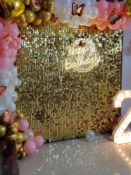 A pretty and playful second birthday setup. The gold sequin wall is paired with a pink and gold balloon arch, accented with butterfly details.