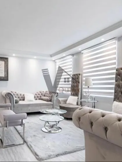 This living room exudes timeless elegance with its classic tufted sofas and high-back armchairs. The monochromatic grey color scheme, paired with glass and chrome coffee tables, creates a sophisticated and formal yet comfortable space.