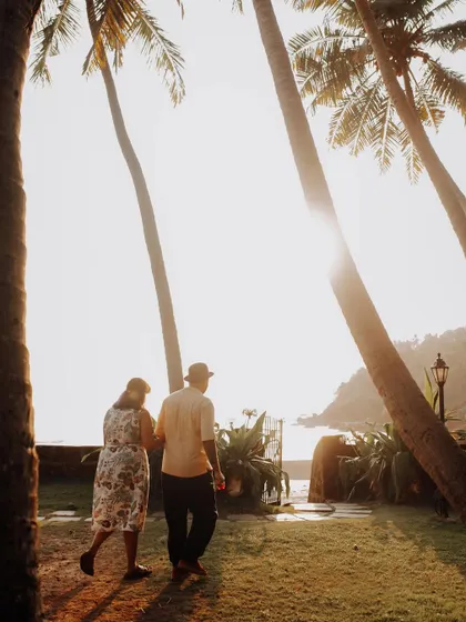 A romantic shot of a couple walking into the sunset on a Goa beach, framed by palm trees. It’s a classic destination pre-wedding moment.