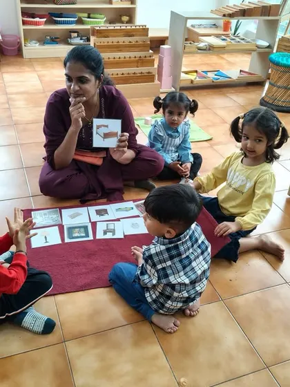 A teacher presents classified picture cards to a small group. This language activity helps build vocabulary and teaches categorization, encouraging conversation and helping children make sense of the world around them.