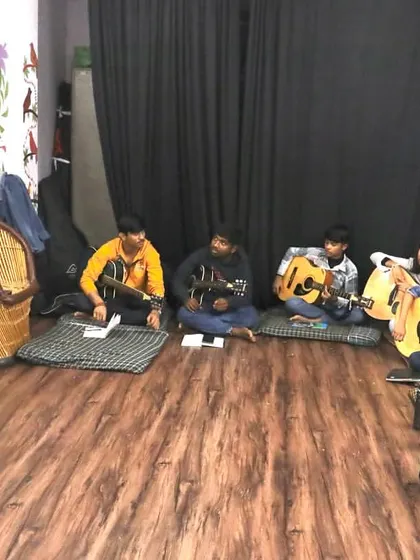 An instructor teaches guitar theory on a whiteboard to a group of attentive students. Our classes balance practical skills with a solid theoretical foundation.