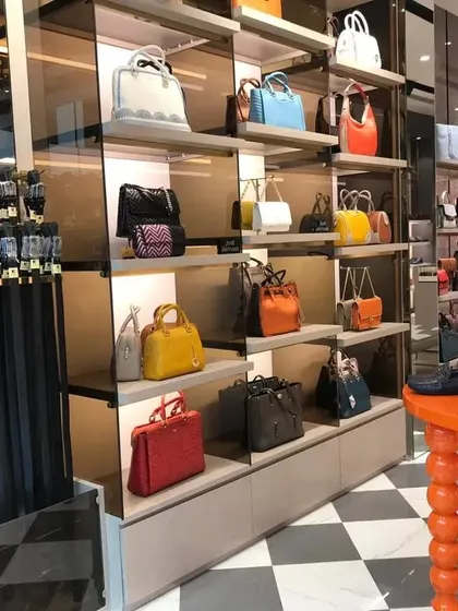 A view showing the belt display on the left and the main handbag section on the right, with a central orange table adding a pop of color.