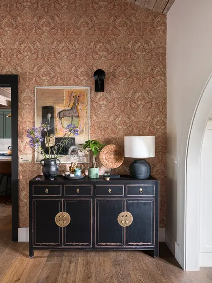 A closer look at the black lacquer console in the Saratoga home. The piece is a beautiful example of modern Indian craftsmanship, with its clean lines and traditional brass hardware. It’s paired with contemporary art and a patterned wallpaper.