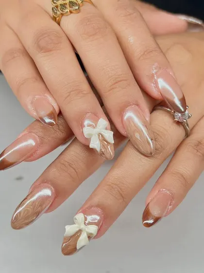 A sweet and sophisticated design with a brown chrome French tip and delicate 3D white bow accents.