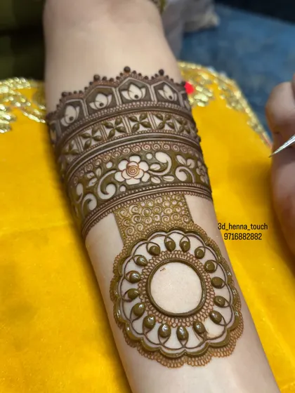 A close-up of the hanging mandala element being added to the lotus arm band. The fine details and swirls make it look like a piece of traditional jewelry.
