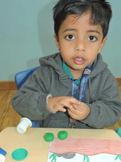 A young boy concentrates on rolling green clay, preparing to model a creature from the underwater world.