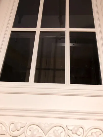 A close-up of a classic white door with glass panels, highlighting the detailed molding and craftsmanship.