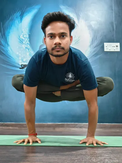 A student holds a challenging arm balance, demonstrating core strength and intense focus.