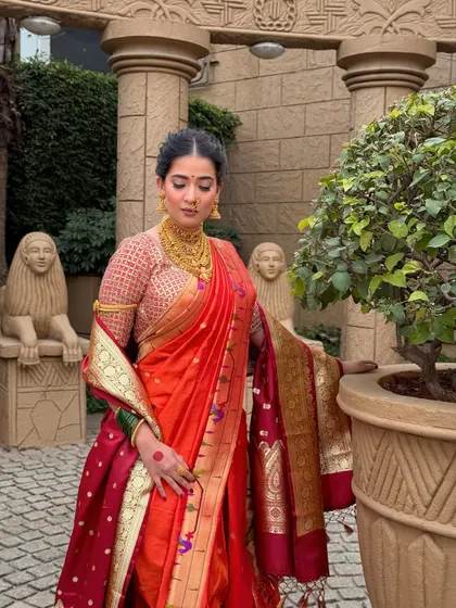 Posed against a classic architectural backdrop, this bride embodies royal elegance. Her makeup is flawless yet understated, allowing the rich colours of her saree to shine.