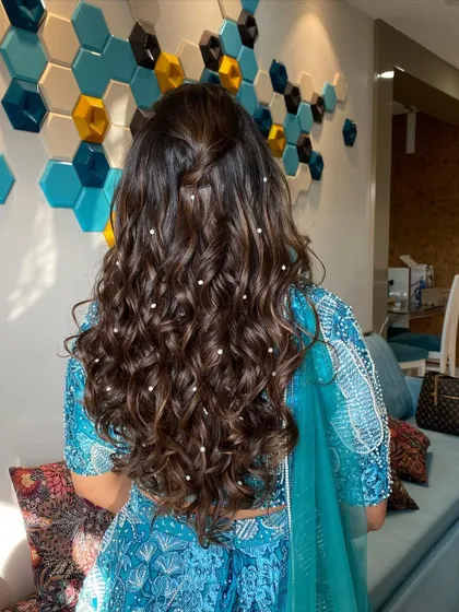A detailed shot of the romantic, curly hairstyle dotted with pearls. It's the perfect complement to her elegant and modern bridal look.