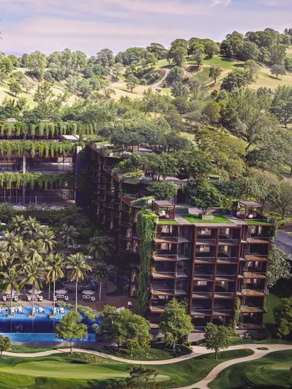 An aerial view of the Westin Nashik, nestled in a green valley. The design uses cascading green roofs and facades to merge the structure with the hilly terrain, creating a harmonious and sustainable retreat.