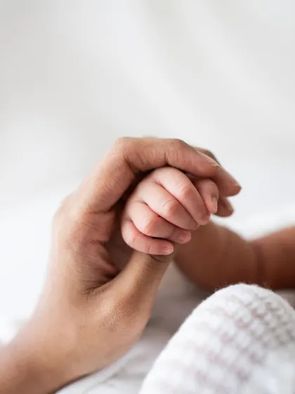 A newborn's hand grasping a parent's thumb. A simple, clean, and powerful image of connection.