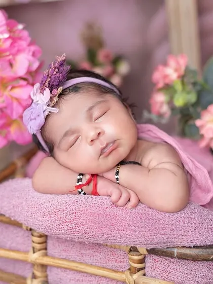 The 'potato sack' wrap pose is perfect for keeping newborns snug and sleepy. The pink tones are lovely for a baby girl.