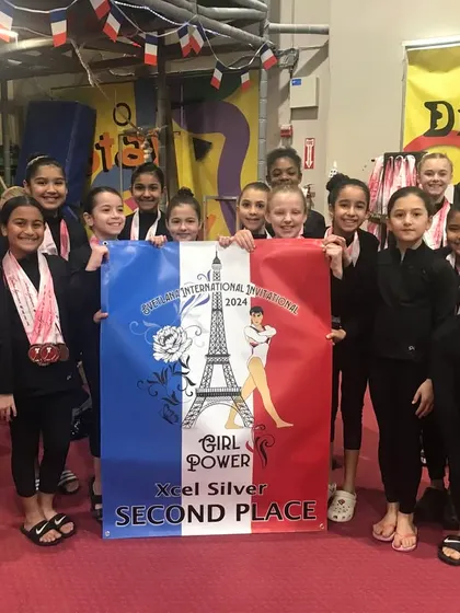 The Xcel Silver team proudly holds their 2nd place banner at the Svetlana Invitational.