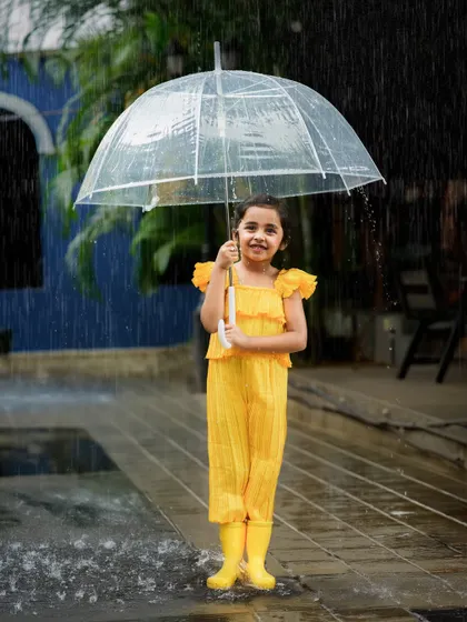 A rainy day doesn't stop the fun. A clear umbrella and bright yellow boots make for a cheerful and unique photoshoot in the rain.