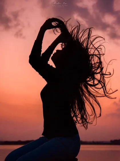 A beautiful silhouette of a woman flipping her hair against a sunset sky, a classic example of creative and expressive portrait photography.