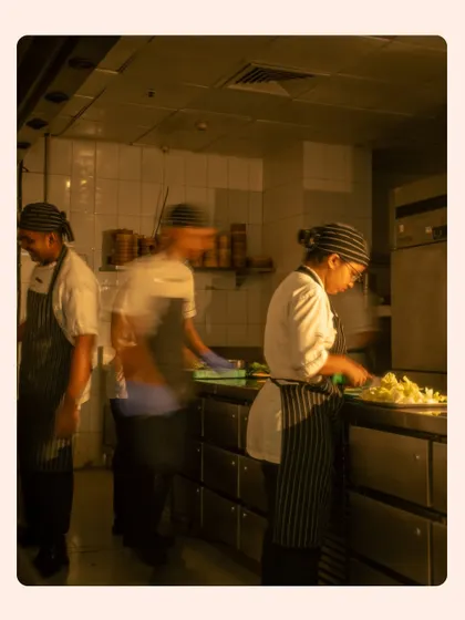 A long-exposure shot capturing the hustle and bustle of a professional kitchen. The motion blur conveys a sense of energy and teamwork, giving a glimpse into the heart of the restaurant.