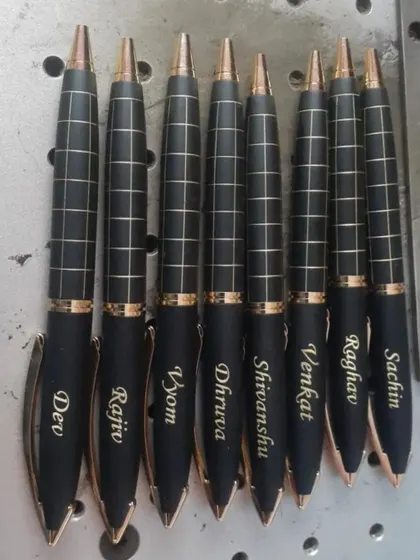 A set of personalized pens with a checkered design, each engraved with a different name. The rose gold accents give them a very modern look.