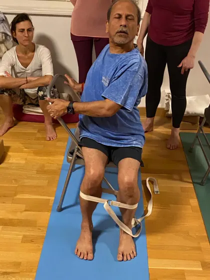 A seated twist using a chair, demonstrated during a workshop at Yoga Des Bains in Geneva. The strap around the knees helps to keep the lower body stable.