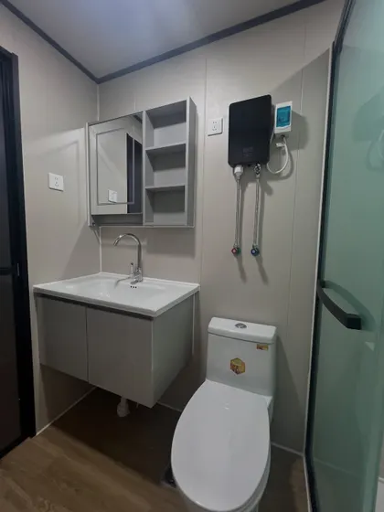 Another view of a modular home bathroom, showing the vanity, mirrored cabinet for storage, and an energy-efficient water heater. Every detail is planned for practicality.
