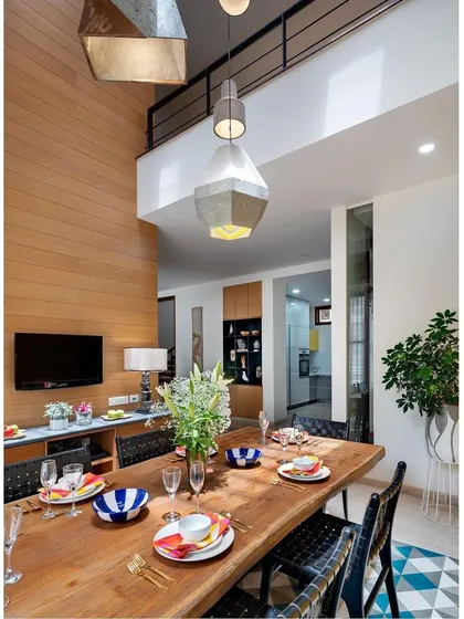 A view of the double-height dining space from the upper level, highlighting the volume and the dramatic cluster of concrete pendant lights.