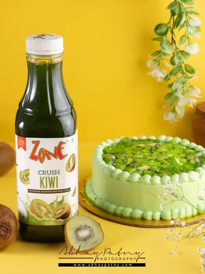 This image pairs a kiwi-flavored drink with a matching kiwi cake. This cross-promotional styling helps showcase how different products from a brand can be enjoyed together.