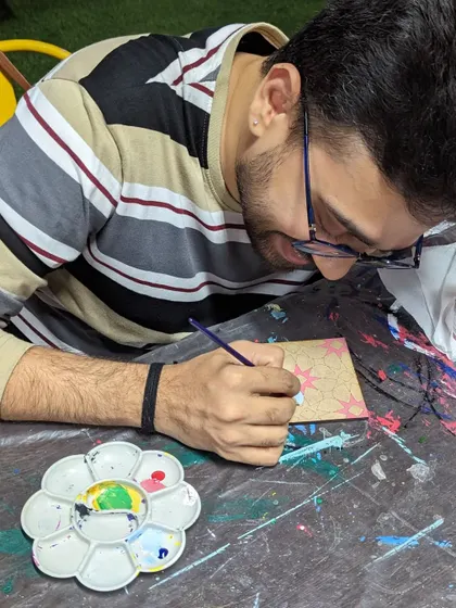 A participant engrossed in his coffee painting, adding fine details to his artwork.