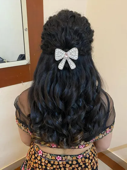 A cute and modern hairstyle with soft curls and a half-up twist, secured with a pearl and crystal bow clip.