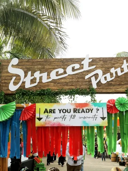 The entrance to a "Street Party" themed event. The rustic wooden sign and colorful streamers create a fun, festival-like vibe from the moment guests arrive.