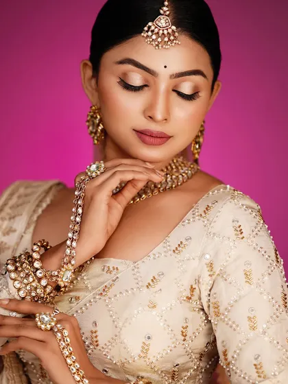 This pose highlights the intricate hand jewelry, or 'hath phool'.