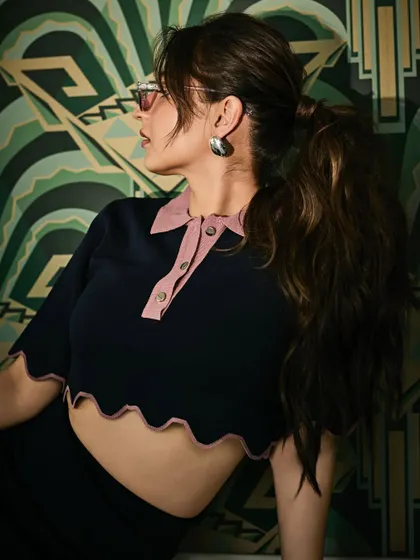 A side profile that gives a better look at the retro-style tinted sunglasses and the clean silhouette of her ponytail.