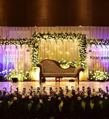 A classic stage setup with white floral frames and purple lighting, suitable for welcoming guests or for smaller functions.