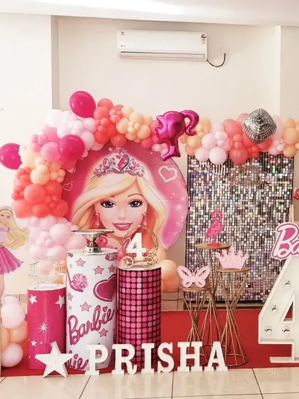 A glamorous Barbie themed 4th birthday party with a pink shimmer wall, Barbie cutouts, and a pink and orange balloon garland.