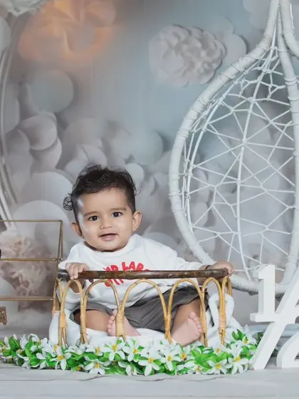 A dreamy half-birthday setup with a white and silver theme, featuring a beautiful hanging chair.