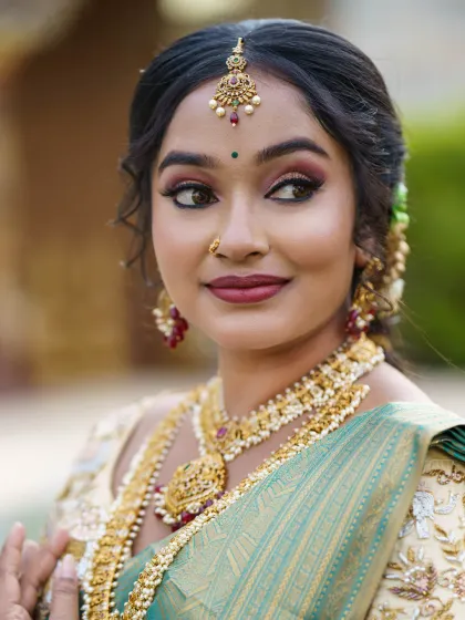 An elegant three-quarter profile of a bride, showing the harmony between her makeup, jewellery, and soft, romantic hairstyle.