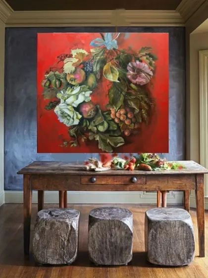 This vibrant floral wreath painting on a bold red background makes a stunning statement in a rustic dining area. We love creating art that contrasts with and enhances the surrounding decor.