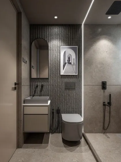 A straight-on view of the grey bathroom vanity area. The fluted paneling behind the toilet adds texture, and the simple arched mirror complements the clean lines of the space. The framed art adds a personal, gallery-like touch.