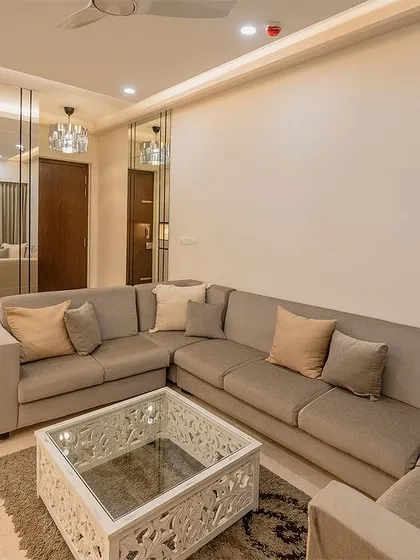 The large L-shaped sofa provides ample seating for guests, while the ornate white coffee table adds a touch of intricate detail to the minimalist space.