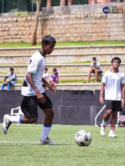 A young footballer dribbles the ball during a training session, his focus embodying the spirit of National Sports Day.