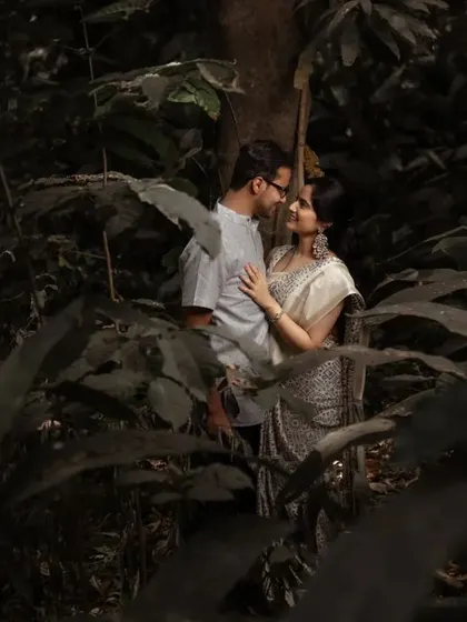 An intimate pre-wedding photo of a couple in a forest, using the natural foliage to create a private, hidden-away feel.
