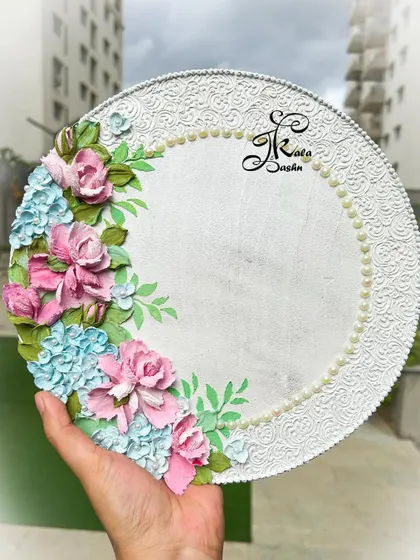 A beautiful 10-inch wedding ring platter with a pastel blue and pink theme. The elegant white base is adorned with sculpted flowers and a pearl border.