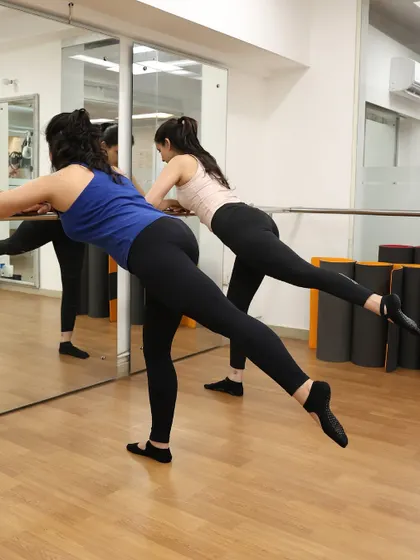 Two members at the barre, performing a leg lift. This move is excellent for targeting the glutes and improving balance.