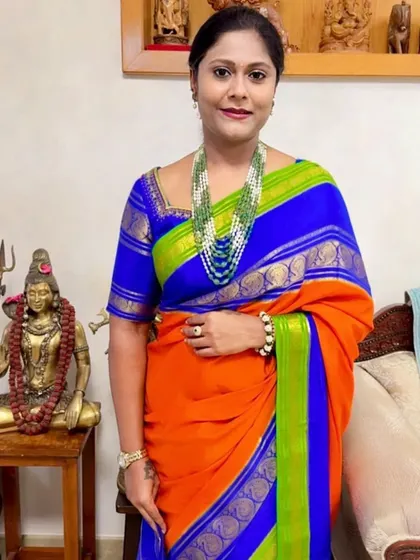 A client looking regal in a vibrant orange and blue 3D pure Mysore crepe saree.