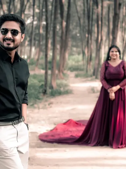 A stylish and relaxed pre-wedding photo. The groom looks sharp in the foreground while the bride's wine-colored trail gown creates a beautiful backdrop.