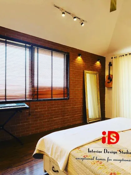 A bedroom with an industrial-chic vibe, featuring an exposed brick wall and track lighting. The space is designed to be a creative's haven, with a keyboard and guitar on display.