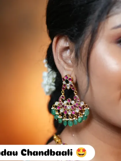 A close-up of the exclusive Jadau Chandbaali earrings, featuring intricate kundan work with ruby and emerald stones.