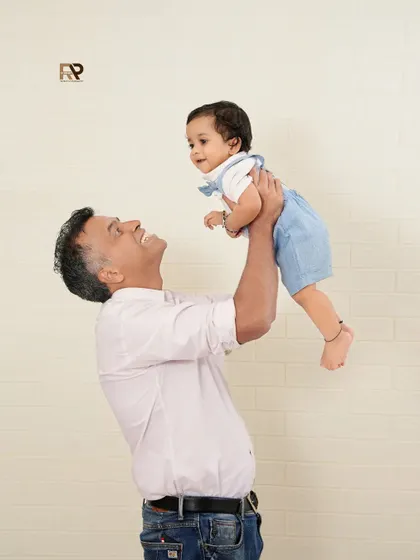 A sweet father-son moment, with dad lifting his baby boy into the air. This classic pose captures the joy and special connection they share.